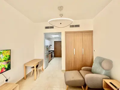 a living room with a couch and a table at Homes2Retreat - Cozy Studio with Pool and Sauna in Al Furjan in Dubai
