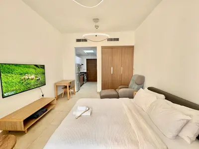 a bedroom with a bed and a living room at Homes2Retreat - Cozy Studio with Pool and Sauna in Al Furjan in Dubai