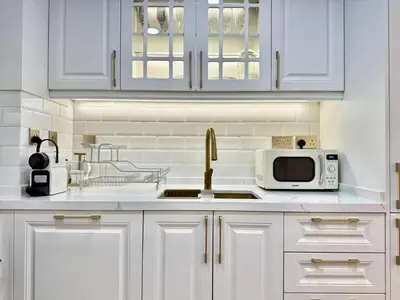 a kitchen with white cabinets and a sink and a microwave at New Modern Marina View Apartment in Bay Central in Dubai