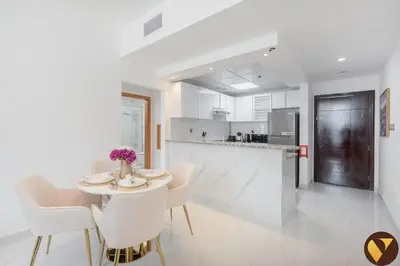 a kitchen and dining room with a table and chairs at Vogue Marina Diamond Near JBR Beach and Marina Mall, One Bedroom Apartment with Balcony and City View, Access to all Amenities, Walkable to Sobha Realty Metro Station and Bus Stop in Dubai