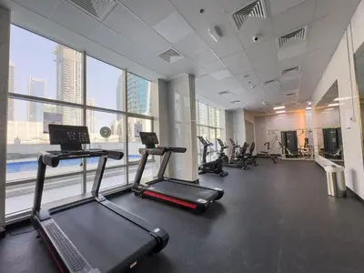 a gym with cardio equipment in a large room with windows at Vogue Marina Diamond Near JBR Beach and Marina Mall, One Bedroom Apartment with Balcony and City View, Access to all Amenities, Walkable to Sobha Realty Metro Station and Bus Stop in Dubai