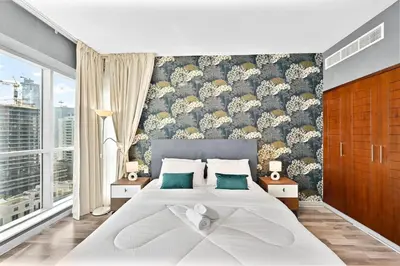 a bedroom with a large white bed with green pillows at Lux 1BR & Steps to Dubai Mall & Burj Khalifa in Dubai