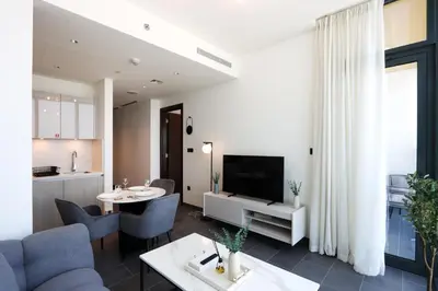 a living room with a dining room table and a kitchen at Stylish 1BR with Skyline Views Sobha Crest, Hartland in Dubai