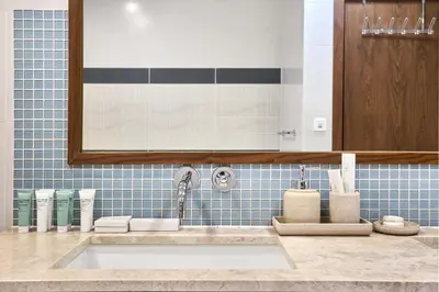 a bathroom with a sink and a mirror and blue tiles at Palm Jumeirah Oasis - Stylish 1 Bedroom Apartment with Garden, Pool & private Beach Access in Dubai