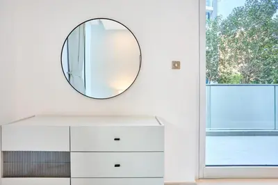 a mirror on a wall above a white dresser at Palm Jumeirah Oasis - Stylish 1 Bedroom Apartment with Garden, Pool & private Beach Access in Dubai
