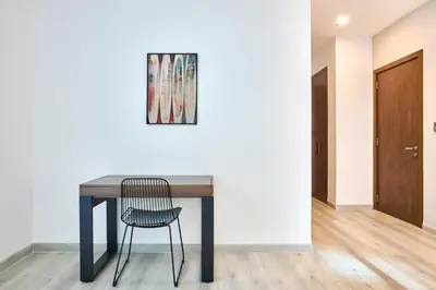 a table with a chair and a painting on a wall at Palm Jumeirah Oasis - Stylish 1 Bedroom Apartment with Garden, Pool & private Beach Access in Dubai