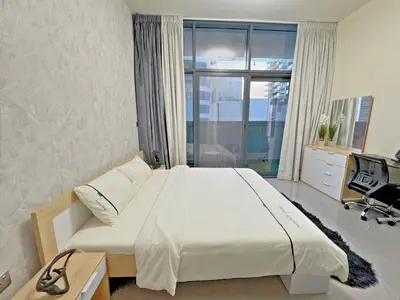 a bedroom with a bed and a desk and a window at Bright & Cozy 1BR in Business Bay with Skyline Views in Dubai