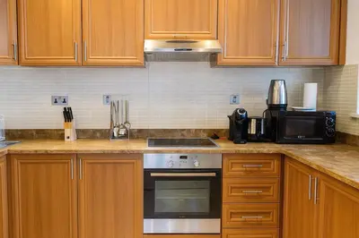 a kitchen with wooden cabinets and a stove top oven at Luxury 1BR with Marina Views Swimming Pool Gym in Dubai