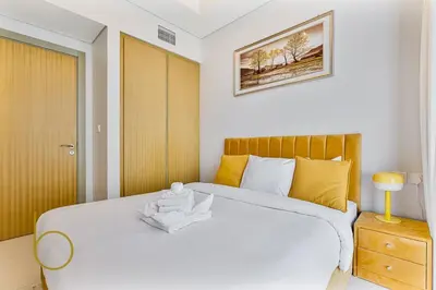 a bedroom with a large white bed with yellow pillows at Bookable 2 bed Damac Aykon City with Balcony & Pool access in Dubai