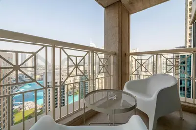 a balcony with a glass table and white chairs at Burj Khalifa View - New Furnished Unit in Downtown in Dubai