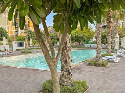 a swimming pool with palm trees in a resort at FIRST CLASS Studio Cozy Comfort in Dubai