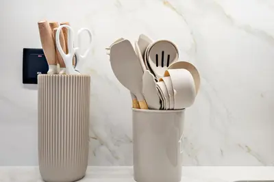 two white containers filled with wooden utensils on a counter at FIRST CLASS 2BR Modern Comfort in the City in Dubai