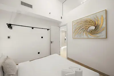 a white room with a bed and a painting on the wall at FIRST CLASS 2BR Modern Comfort in the City in Dubai
