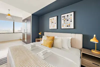 a bedroom with a large white bed and a blue wall at Silkhaus Comfy Studio in Sky Gardens with DIFC Views in Dubai