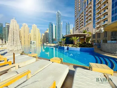 a swimming pool with lounge chairs and a city skyline at The Muse in Dubai