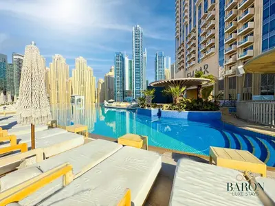 a swimming pool with lounge chairs and a city skyline at The sleek in Dubai