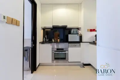 a kitchen with white cabinets and a microwave at The sleek in Dubai