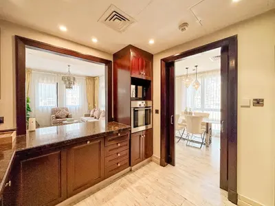 a kitchen with wooden cabinets and a dining room at Royal Escape Burj Khalifa View 2BR in Downtown Dubai in Dubai