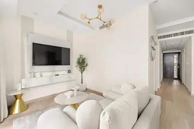a white living room with a white couch and a tv at FIRST CLASS 2BR Luxury Facing Burj Khalifa in Dubai