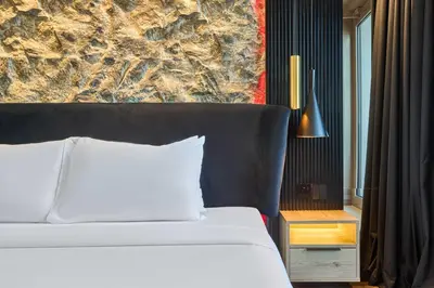 a bedroom with a white bed and a wall at Stylish 1BR Apartment with Marina View, Balcony, Pool & Gym Access in Dubai