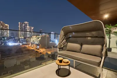 a chair on a balcony with a view of a city at Stylish 1BR Apartment with Pool, Gym & Balcony - JVC Oxford Terraces in Dubai