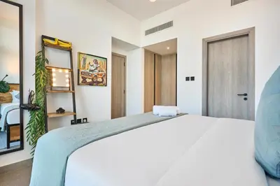 a bedroom with a white bed and a door at Stylish 1BR Apartment with Pool, Gym & Balcony - JVC Oxford Terraces in Dubai