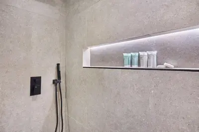 a bathroom with a shower with a shelf with toiletries at Stylish 1BR Apartment with Pool, Gym & Balcony - JVC Oxford Terraces in Dubai