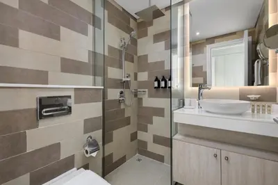 a bathroom with a sink and a glass shower at Maison Privee - Elegant Palm Retreat with Iconic Sea & Marina Vws in Dubai