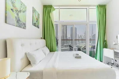 a bedroom with a white bed and a large window at Modern Studio With Iconic Burj Khalifa & Canal Views in Dubai