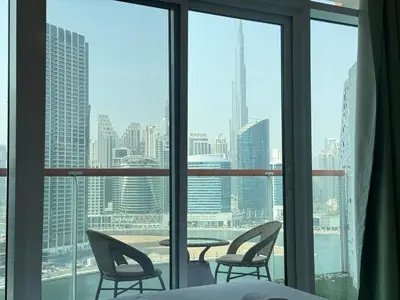 a bedroom with a view of a city from a window at Modern Studio With Iconic Burj Khalifa & Canal Views in Dubai