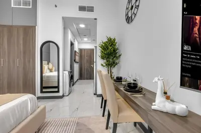 a dining room with a table and chairs and a bed at Classy Studio At Rukan in Dubai