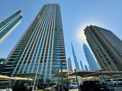 a tall building with cars parked in a parking lot at Luxury 4BR with full Burj Khalifa and Fountain View - 5Min to Dubai Mall in Dubai