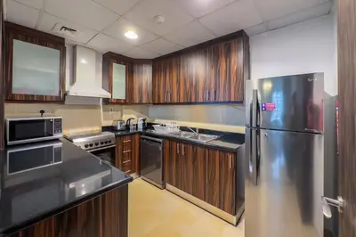 a kitchen with wooden cabinets and a stainless steel refrigerator at 2 Bedroom Apts in JBR Shams 1 by Luxaura in Dubai