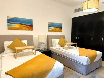 two beds in a hotel room with two tables at 2 Bedroom Apts in JBR Shams 1 by Luxaura in Dubai