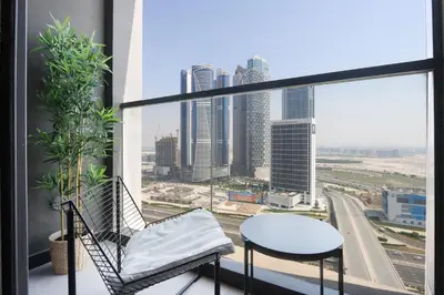 a balcony with a chair and a table and a city at Chic 1B by Dubai Canal Marasi Drive with Pool, Gym in Dubai