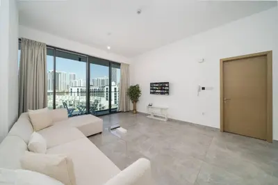 a living room with a white couch and a large window at Chic and Bright JVC 1 Bed in Catch Residences in Dubai