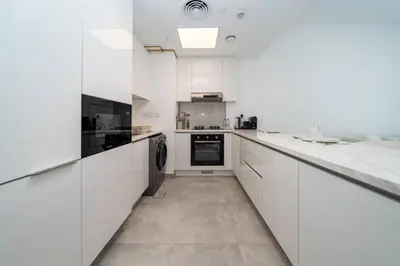 a white kitchen with white cabinets and appliances at Chic and Bright JVC 1 Bed in Catch Residences in Dubai