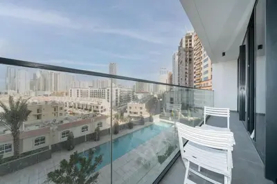 a balcony with a white chair and a view of a city at Chic and Bright JVC 1 Bed in Catch Residences in Dubai