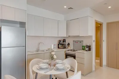 a kitchen with white cabinets and a table and chairs at Highest floor - 5 mins walk to Dubai Mall and Burj Khalifa in Dubai