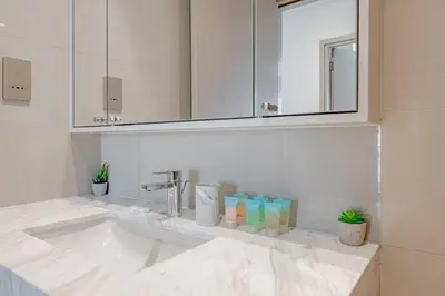 a white bathroom with a sink and a mirror at Highest floor - 5 mins walk to Dubai Mall and Burj Khalifa in Dubai
