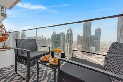a balcony with two chairs and a table with food at Walk to Dubai Mall and Burj Khalifa Luxury 2 Bed - sleep up to 10 in Dubai