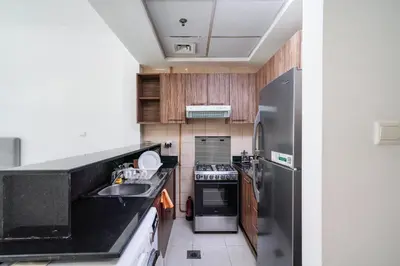 a kitchen with a sink and a stainless steel refrigerator at Cozy Studio at walking distance from Burj Khalifa and Downtown Dubai in Dubai