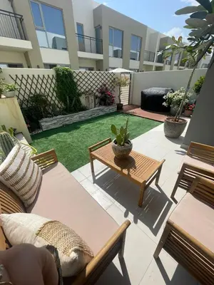 a patio with chairs and a table and grass at Bright & Stylish 4BR Villa in Dubai