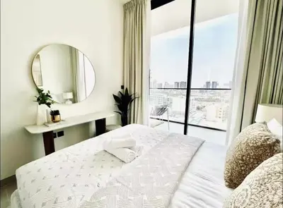 a bedroom with a white bed and a mirror at High Floor apartment in Jumeirah Village Circle in Dubai