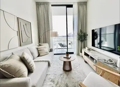 a living room with a white couch and a tv at High Floor apartment in Jumeirah Village Circle in Dubai