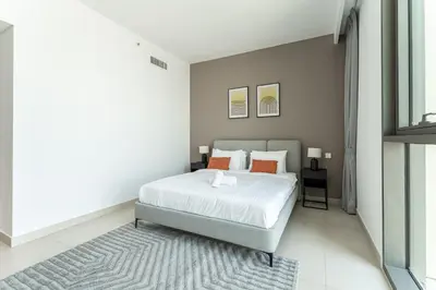 a bedroom with a bed with white sheets and orange pillows at HAVN - 2 bedroom in Downtown Views Dubai in Dubai