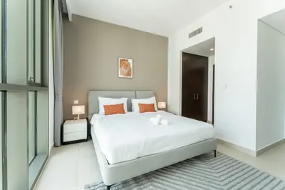 a bedroom with a large white bed with orange pillows at HAVN - 2 bedroom in Downtown Views Dubai in Dubai