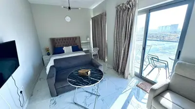 a room with a couch and a bed and a glass table at Studio in May 5 Boulevard in Dubai