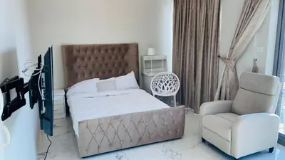 a bedroom with a large bed and a chair at Studio in May 5 Boulevard in Dubai