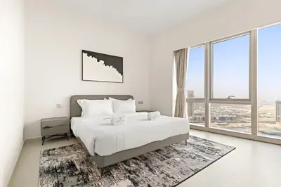 a white bedroom with a bed and a large window at FIRST CLASS 1BR Burj Khalifa & Skyline Views in Dubai
